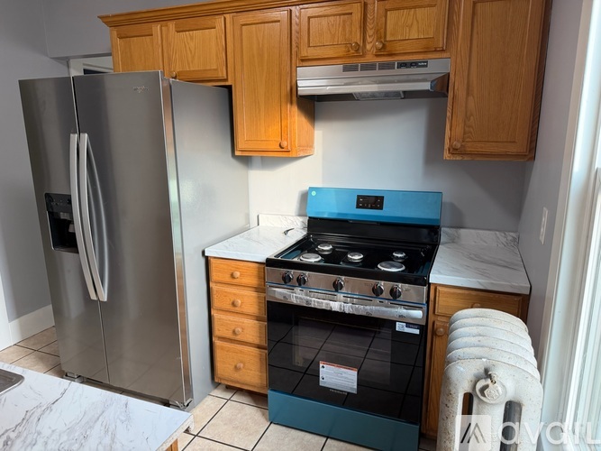 A kitchen with a refrigerator, oven, and cabinets.