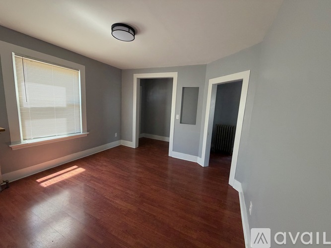 A room with wooden floors and a window with blinds.