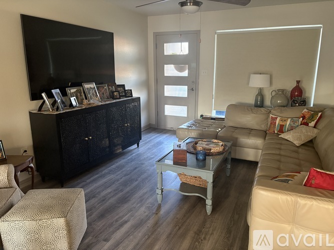 A living room with a black entertainment unit, a beige sofa, and a glass coffee table.