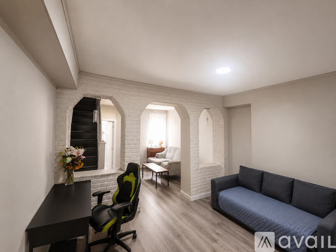 A modern living room with a black sofa, a black desk, and a green office chair.