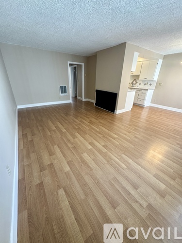 A room with wooden flooring and a wall-mounted TV.