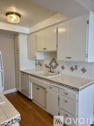 A kitchen with white cabinets and a tiled backsplash.