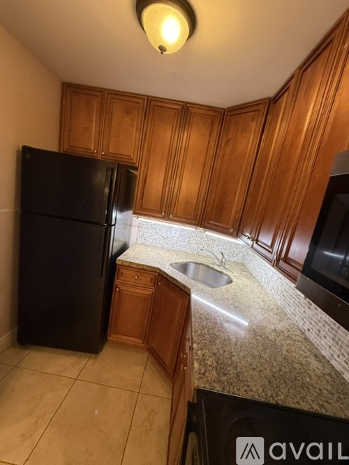 A kitchen with wooden cabinets and a black refrigerator.