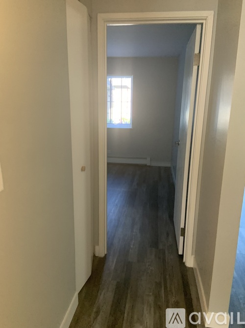 A hallway with a wooden floor and white walls.