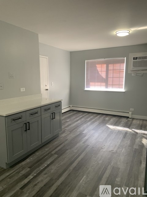 A kitchen with grey cabinets and a wooden floor.