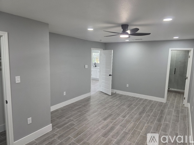 A spacious room with a ceiling fan and lighting fixtures.