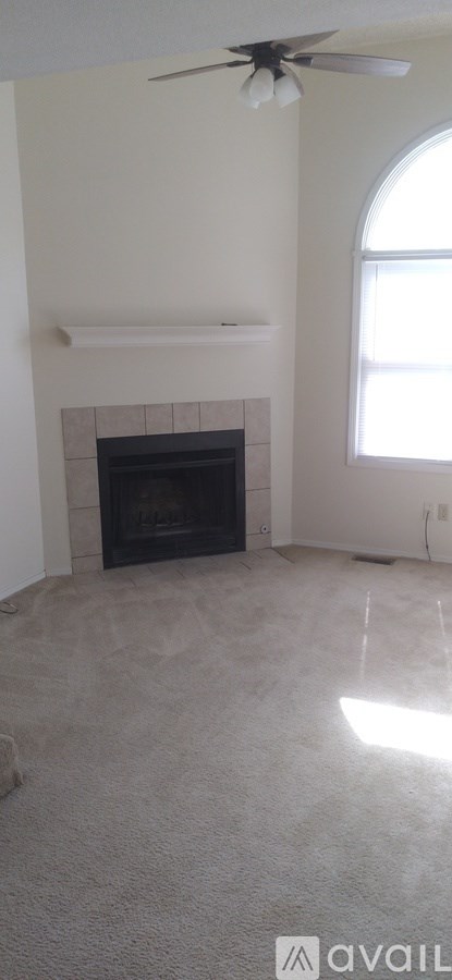 A living room with a fireplace and a ceiling fan.