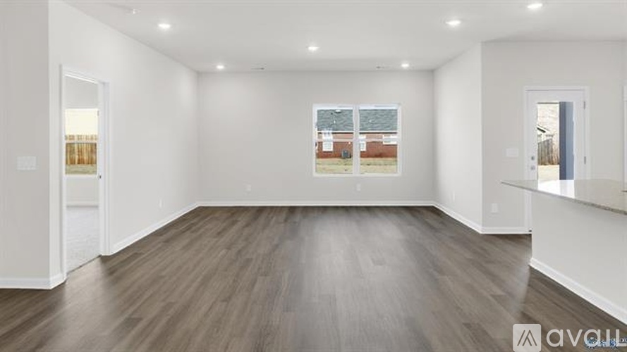 A spacious room with wooden flooring and white walls.