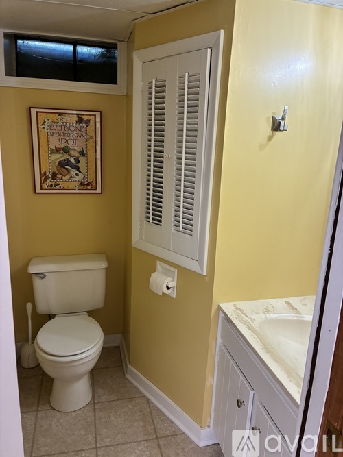 A bathroom with a toilet, sink, and a picture on the wall.