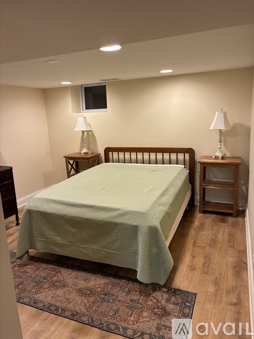 A bedroom with a bed, two lamps, and a rug.
