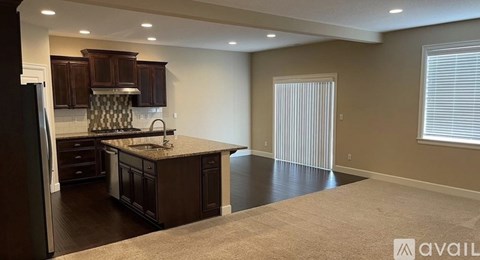 A kitchen with dark wood cabinets and a granite countertop.
