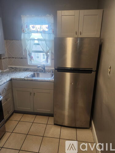 A kitchen with a stainless steel refrigerator and white cabinets.