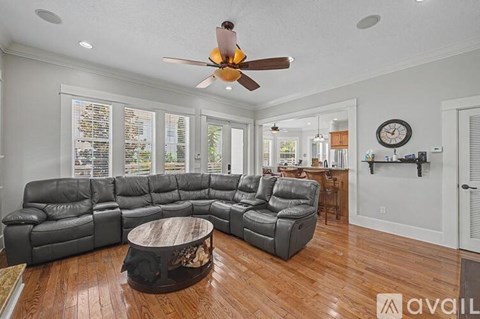 A living room with a black leather sectional sofa and a wooden coffee table.