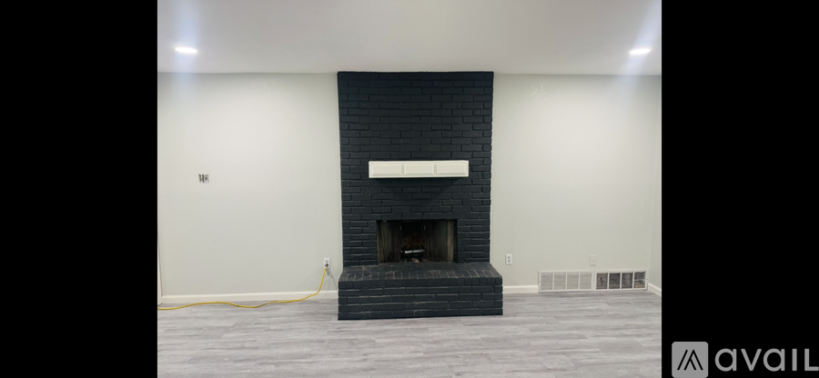 A modern fireplace with a black mantle and a white shelf above it.