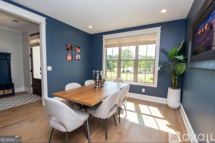 A dining room with a wooden table and white chairs.