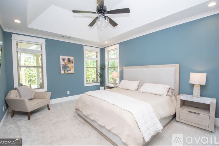 A bedroom with a large bed, a chair, and a ceiling fan.