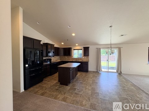 A spacious kitchen with dark cabinets and a tiled floor.