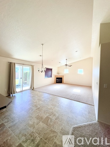 A spacious living room with a grey tiled floor and a large window with curtains.