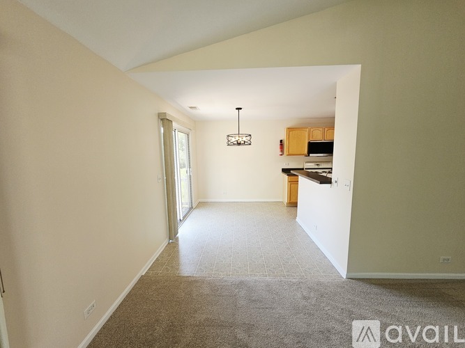 A spacious room with a carpeted floor and a chandelier hanging from the ceiling.