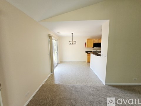 A spacious room with a carpeted floor and a chandelier hanging from the ceiling.