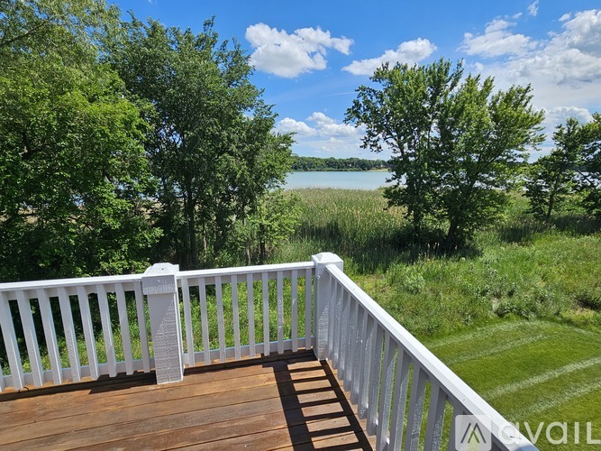 A deck overlooks a body of water with trees in the background.