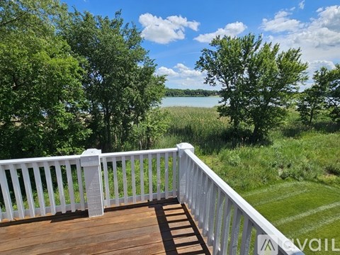 A deck overlooks a body of water with trees in the background.