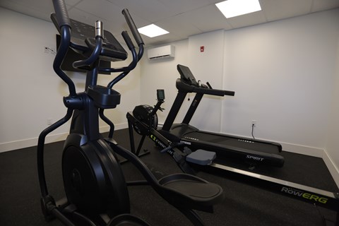 A gym with a treadmill, elliptical trainer and a stationary bike.