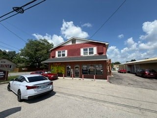 A white car is parked in front of a red building.