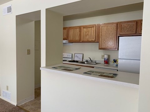 A kitchen with white countertops and wooden cabinets.