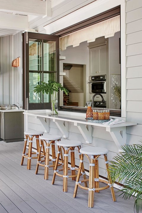 A white bar with stools is on a wooden deck.