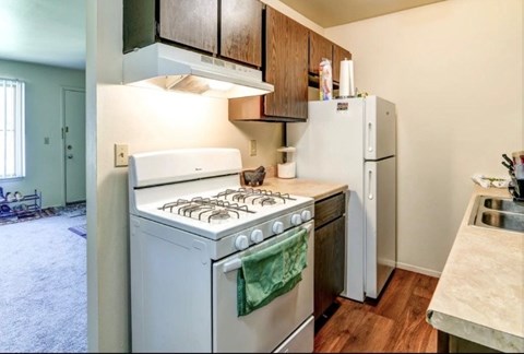 A kitchen with a white stove and refrigerator.