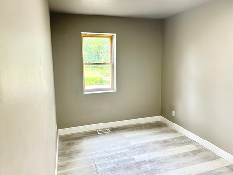A room with a window and wooden flooring.