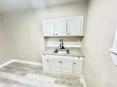 A kitchen with a granite countertop and white cabinets.