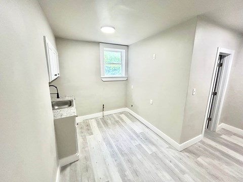 A room with a window, sink, and wood flooring.