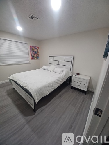 A bedroom with a white bed and a grey carpet.