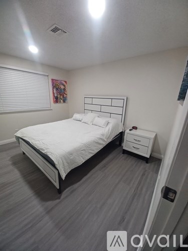 A bedroom with a white bed and a grey carpet.
