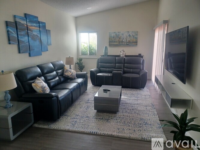 A living room with black leather furniture and a flat screen TV.