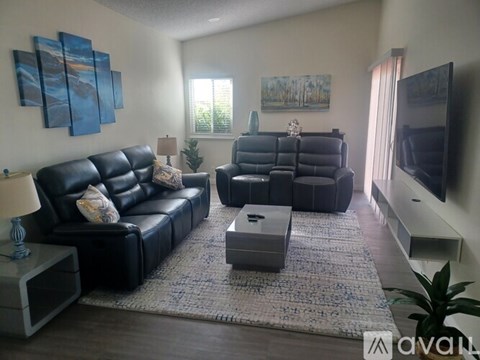 A living room with black leather furniture and a flat screen TV.