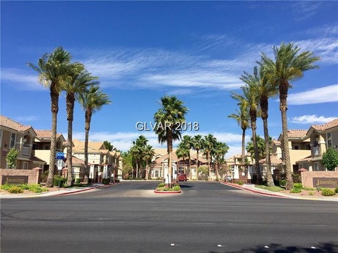 A street view of a residential area with palm trees and houses.