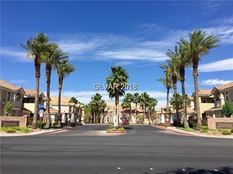 A street view of a residential area with palm trees and houses.