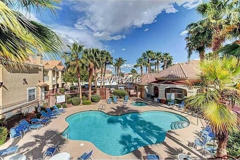 A pool surrounded by palm trees and lounge chairs.