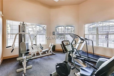 A gym with a treadmill, weights, and a bench press.