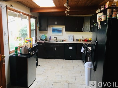 A kitchen with black cabinets and a black fridge.