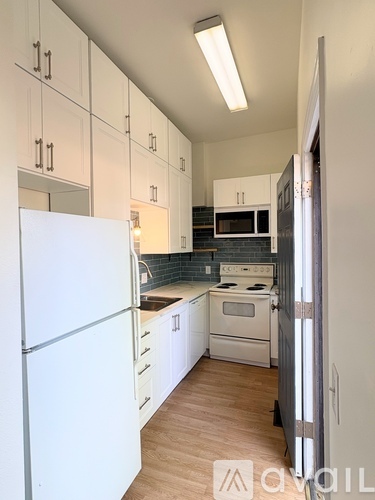 A kitchen with white appliances and cabinets.