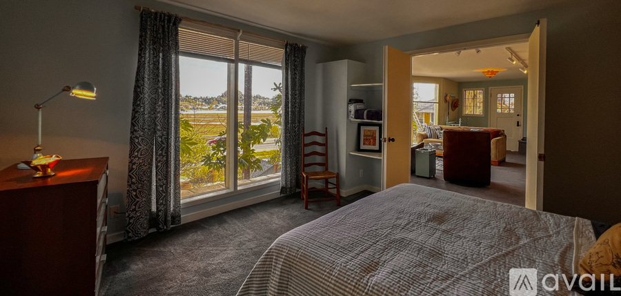 A bedroom with a large bed and a view of the outdoors through the window.