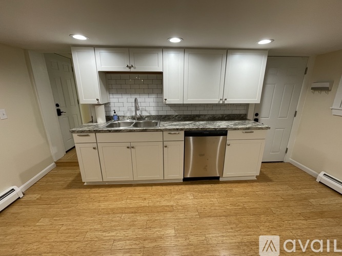 A kitchen with white cabinets and a black countertop.