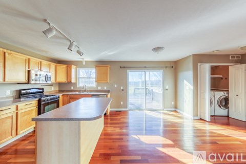 A kitchen with wooden cabinets and a large island in the middle.