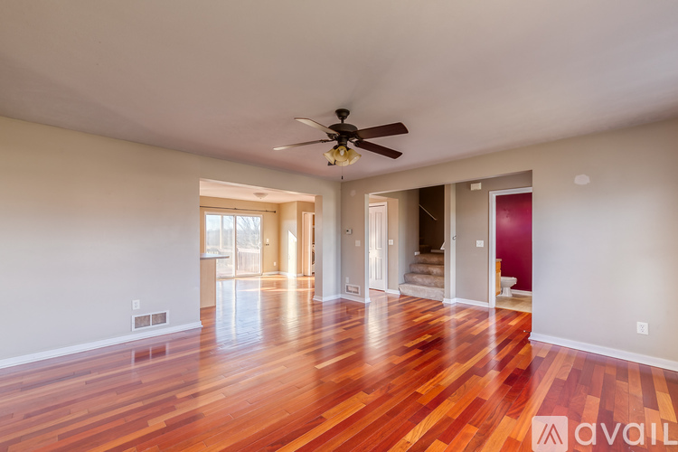 A spacious room with wooden floors and a ceiling fan.