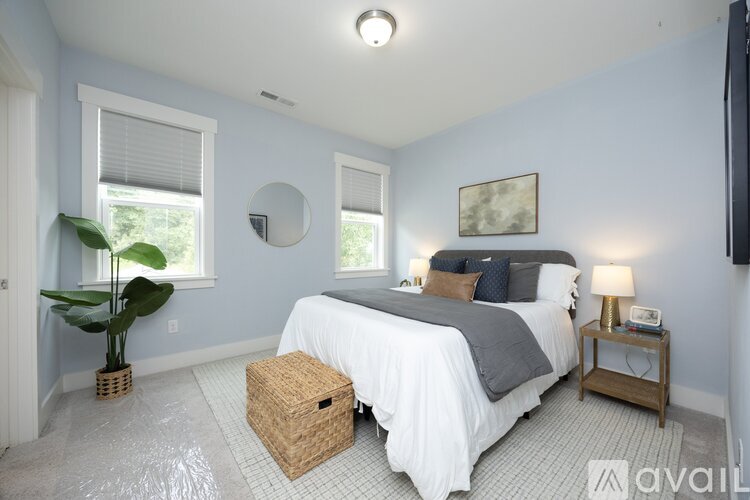 A bedroom with a bed, a plant, and a mirror on the wall.