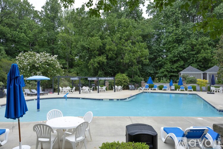 A pool area with blue umbrellas and white chairs.